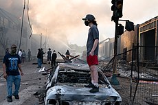 230px-A_man_stands_on_a_burned_out_car_on_Thursday_morning_as_fires_burn_behind_him_in_the_Lake_St_area_of_Minneapolis%2C_Minnesota_%2849945886467%29.jpg